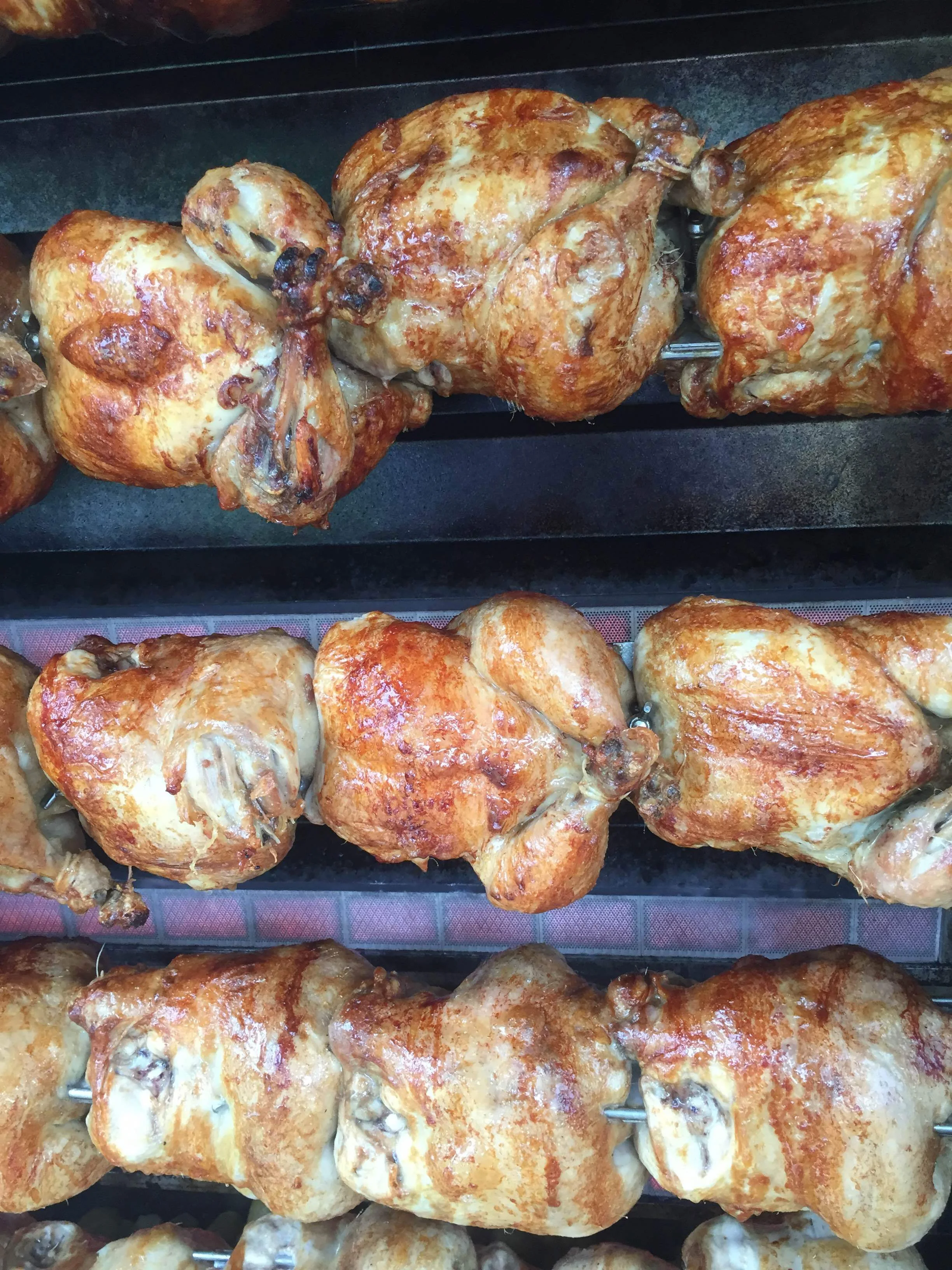 Golden rotisserie chickens on the spit — close up